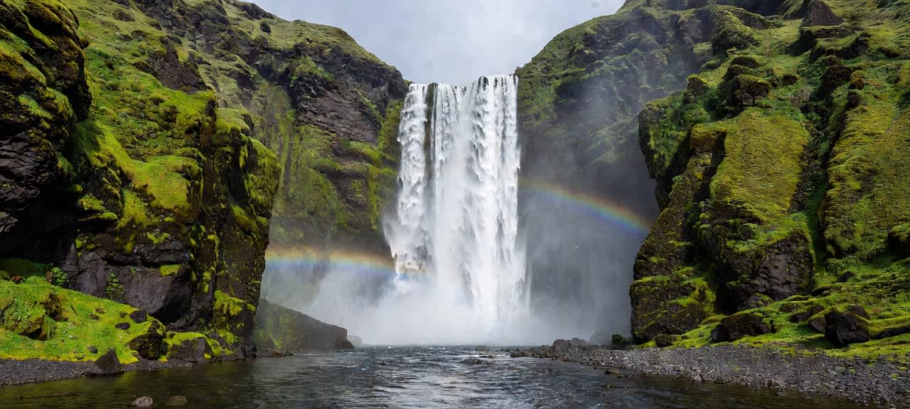 Majestic Waterfall Rainbow Over Mossy Cliffs — desktop wallpaper preview