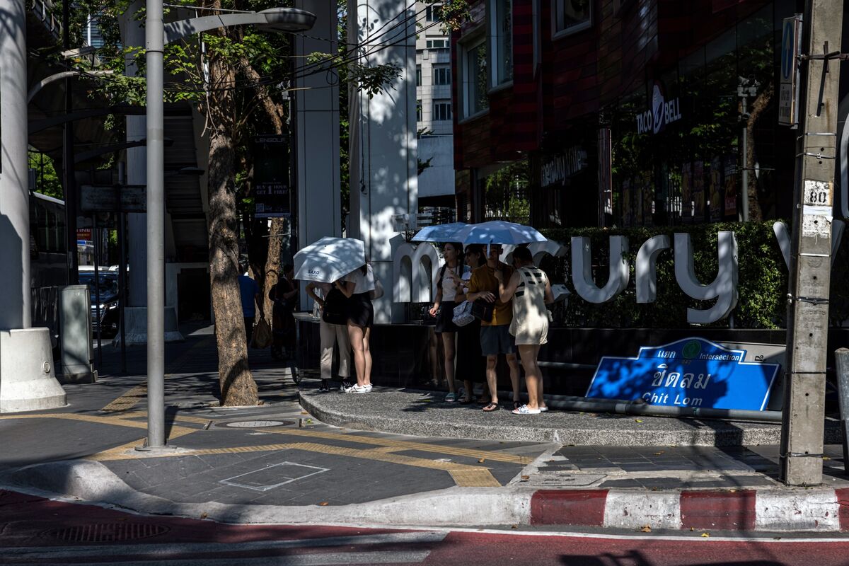 Pedestrians shade from the sun during high temperatures in Bangkok.