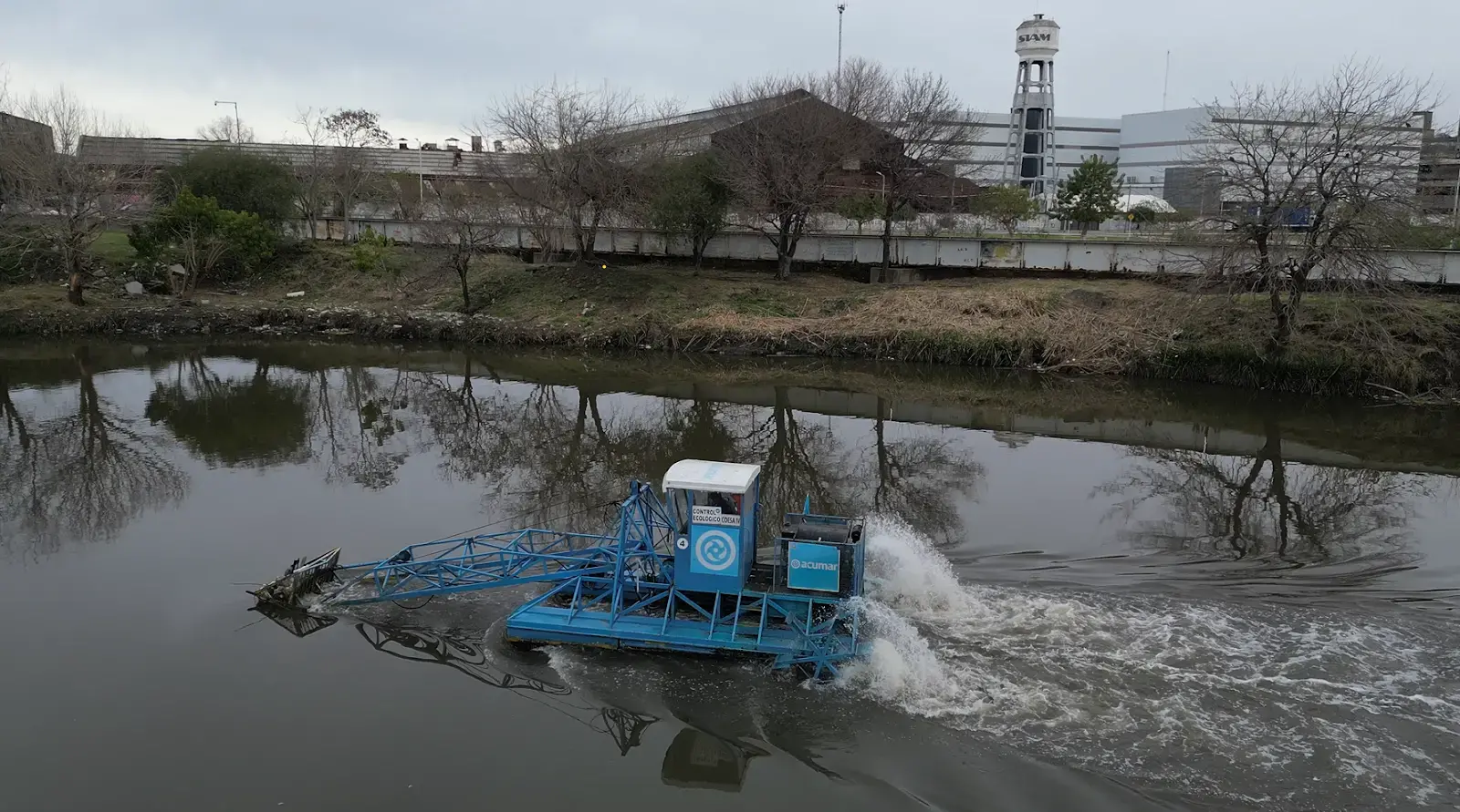 A slow-moving catamaran operated by the Autoridad de Cuenca Matanza Riacheulo (ACUMAR) turns a corner near Villas 21-24 in the Autonomous City of Buenos Aires as it sifts garbage from the river into its collection bucket, 2023.