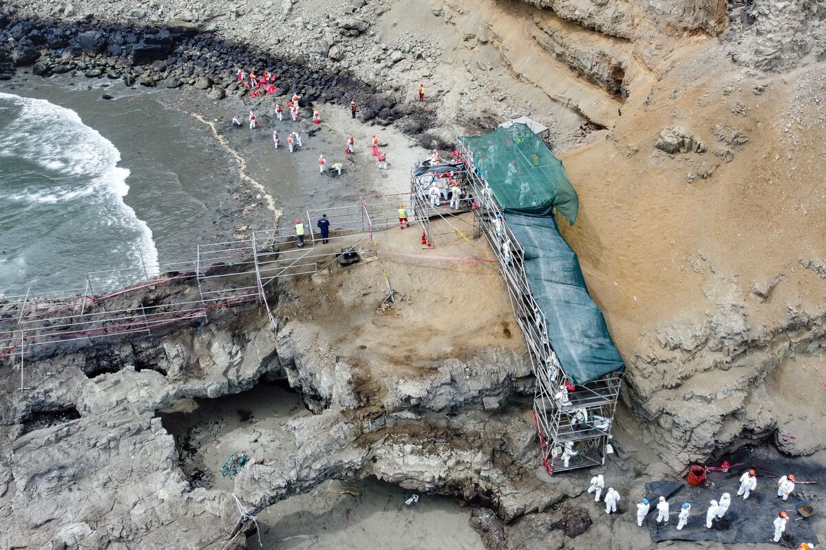 Workers clean up Cavero Beach after an oil spill in Callao, Peru, February 18, 2022.