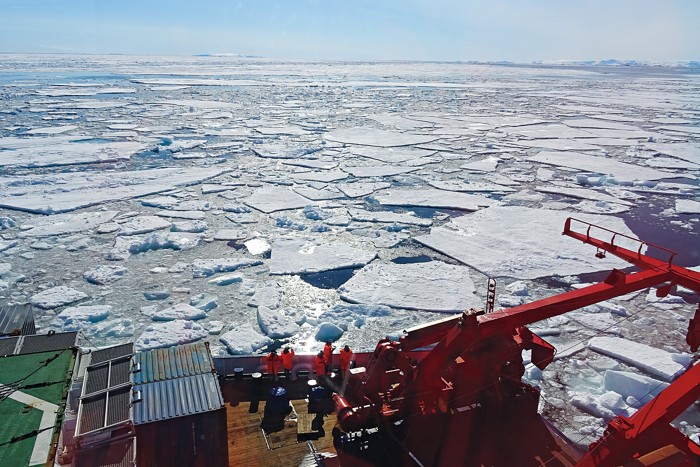 A research vessel travels through ice floes so researchers aboard can sample the environment for pollution levels.