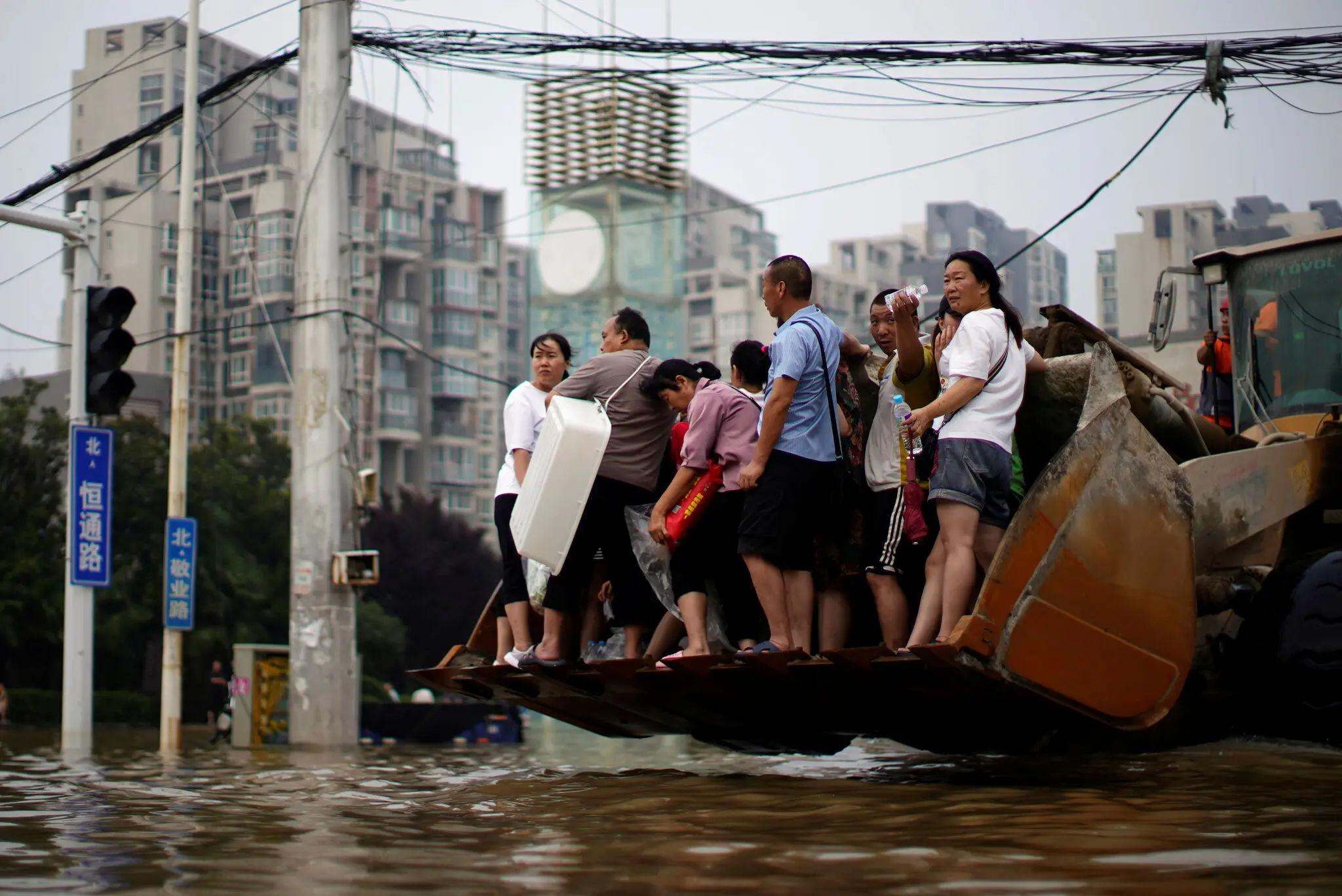 Riding on a front loader through floodwaters in Zhengzhou, Apr 19, 2024.