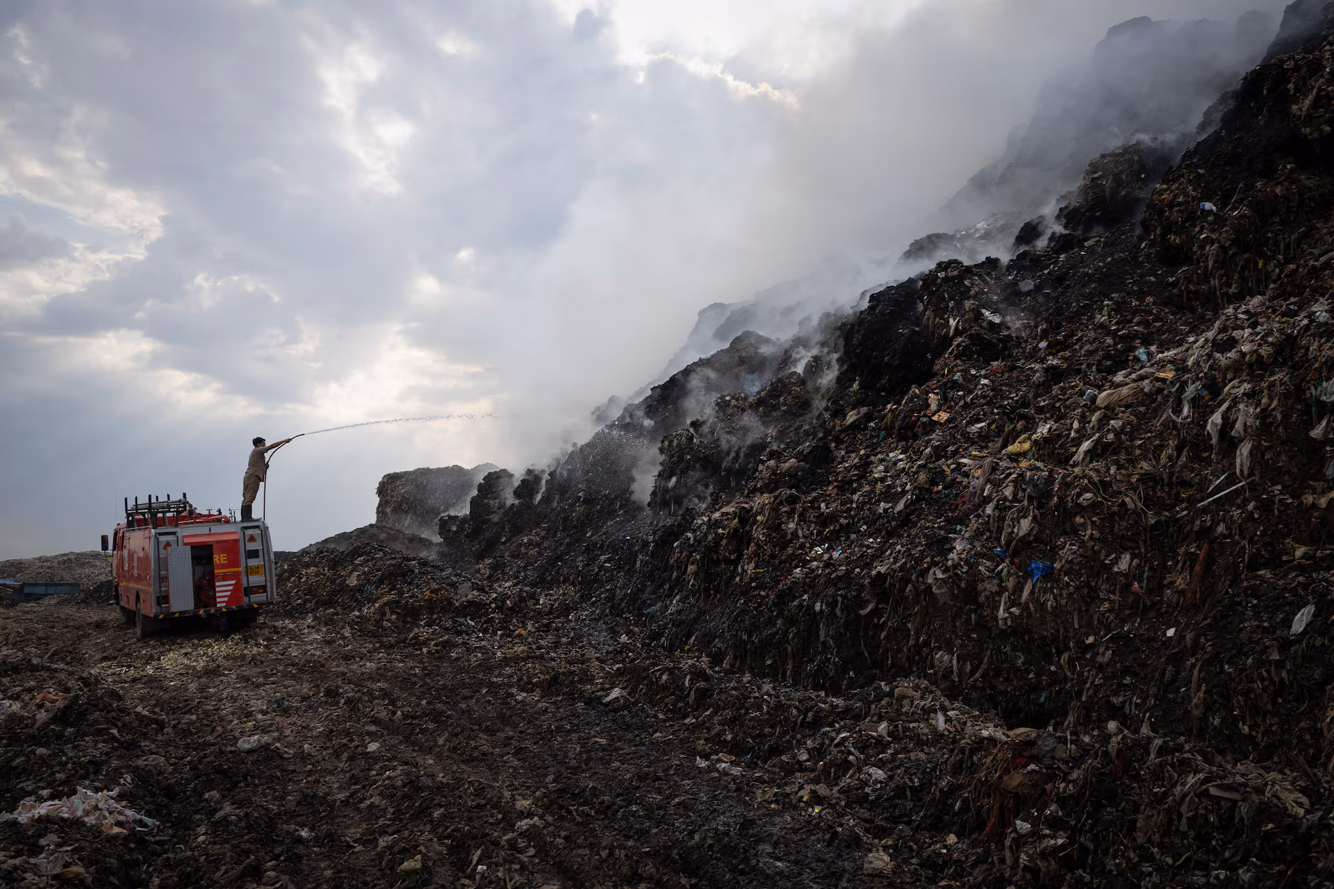 A firefighter works to douse fire as smoke billows from burning garbage at the Ghazipur landfill site in New Delhi, India, April 22.