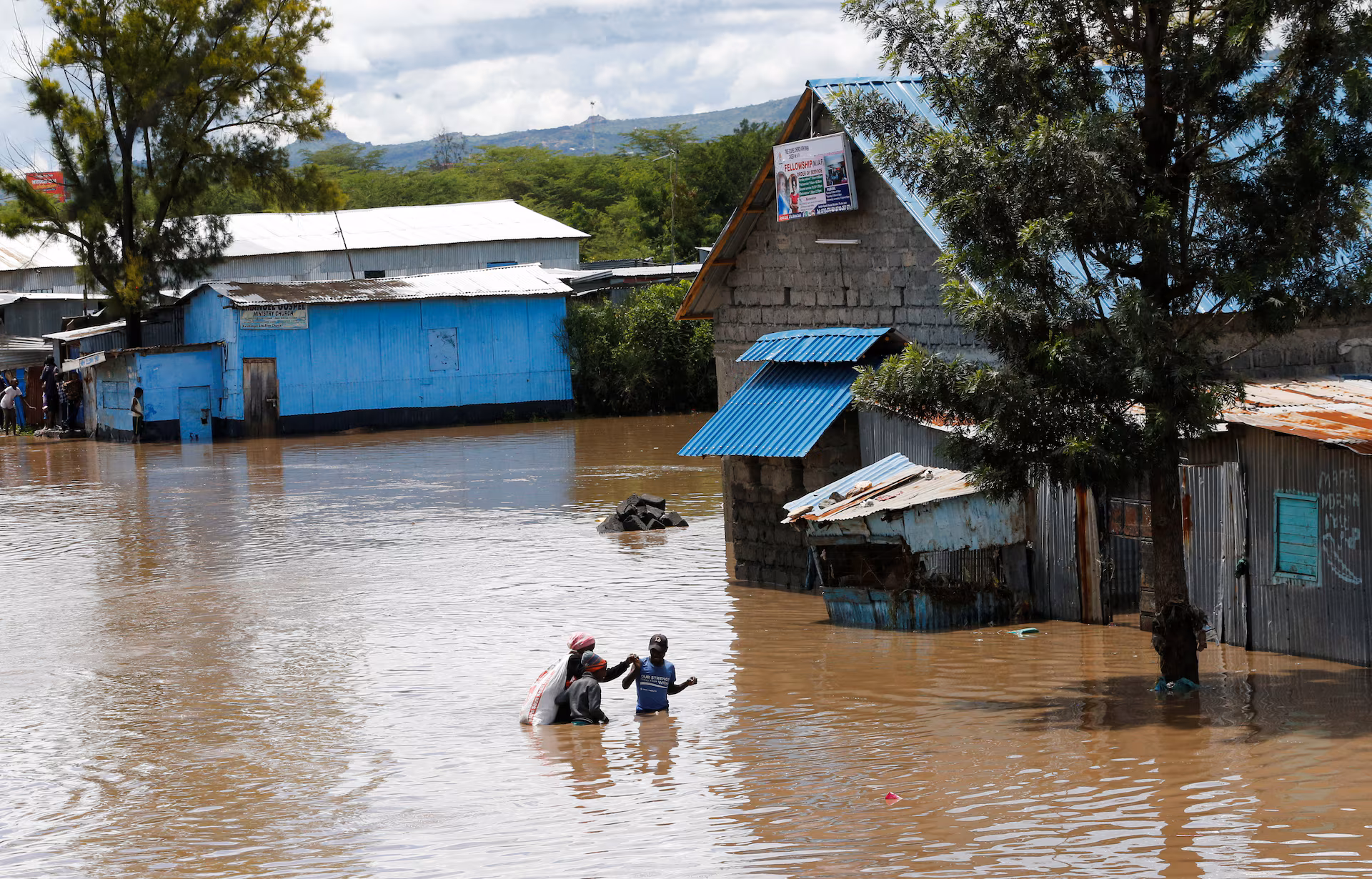 Residents wade through flash flood waters after Athi River burst its banks following heavy rainfall in Kwa Mang'eli settlement of Machakos county near Nairobi, Kenya April 24.