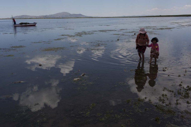 In this Feb. 2, 2017 photo, cousins from the Avila family search for discarded toys on the shores of Lake Titicaca, in Coata in the Puno region of Peru. The shores of South America’s largest lake are littered with dead frogs, discarded paint buckets and bags of soggy trash. Less visible threats lurk in the water itself: highly toxic levels of lead and mercury.