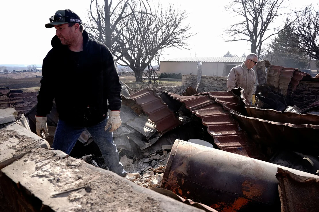 Mason Holloway and Hugh Lively sift through the remains of a relative's home destroyed by the Smokehouse Creek Fire in Canadian, Texas, on February 28, 2024.