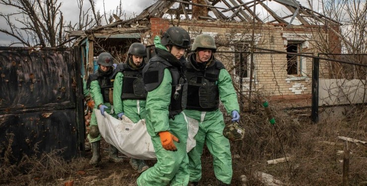 Ukrainian volunteers carry the body of a Russian military man.