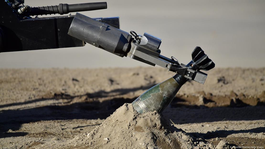 A remote-controlled robot known as tEODor is used to grab a grenade with a manipulator arm.