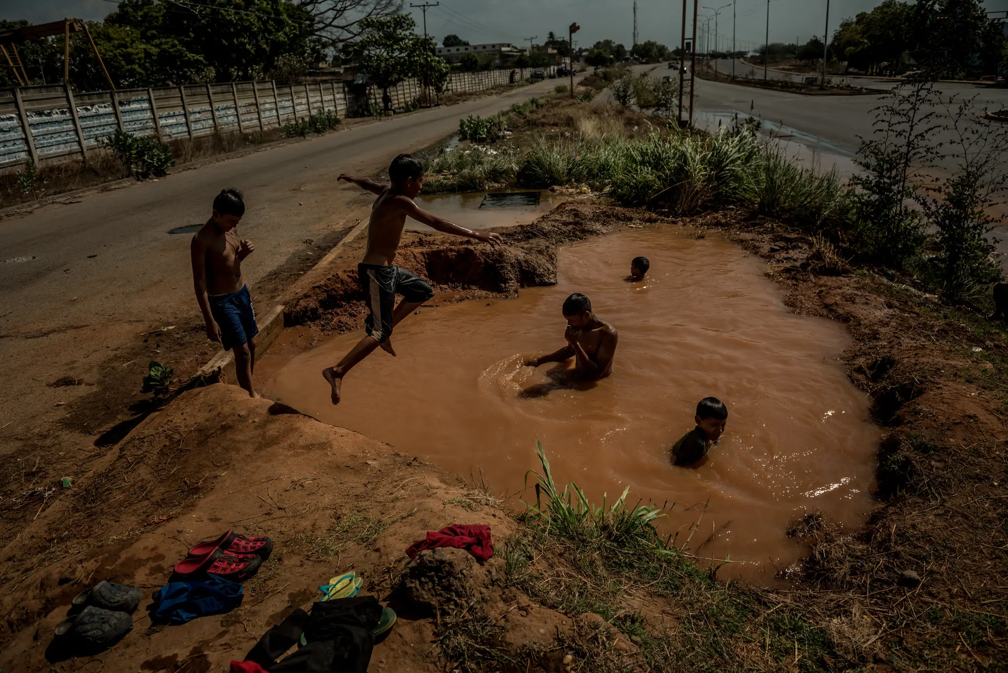 Boys bathe in a makeshift pool in San Felix, Venezuela, that hasn't had running water for months. Often conditions are worse outside of Caracas.