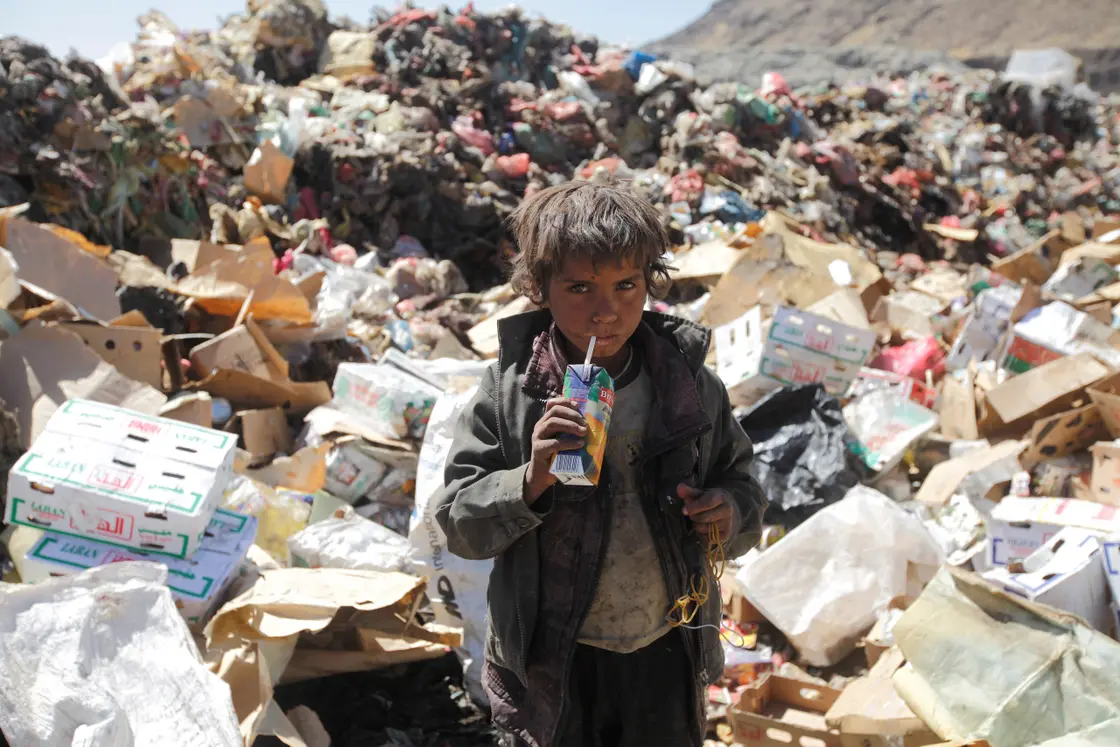 A boy drinks expired juice on a pile of rubbish at landfill site on the outskirts of Sanaa, Yemen