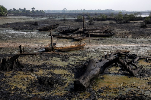 Abandoned fishing boats sit on the ground as crude oil pollution covers the shoreline of an estuary in B-Dere, Ogoni, Nigeria, on Saturday, Feb. 1, 2020