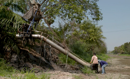 Farmers attempt to install water pumps to draw water from canals into their farms. Some wait weeks at a time for water to be released from the dam into the canal.