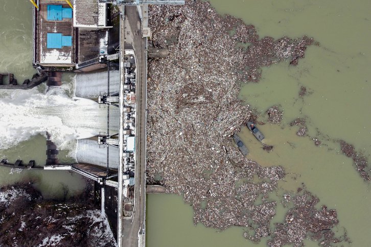 Workers collect plastic trash that litters the polluted Potpecko Lake near a dam's hydroelectric plant