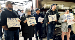 Morrow County residents meet with Oregon Sen. Jeff Merkley about nitrate contamination in their water. They hold up signs showing the nitrate levels in their water.