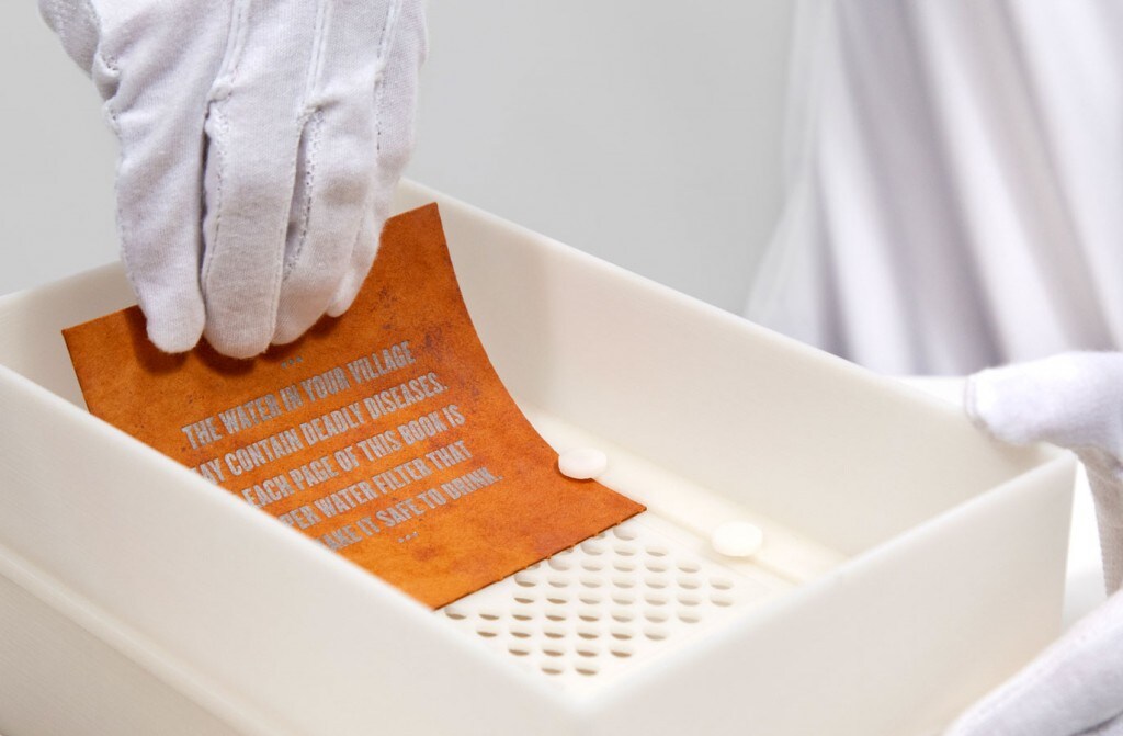 The pages are put into a holding device that allows water to pass through