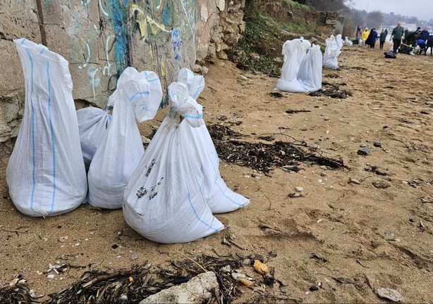 The bags of fuel oil collected by volunteers are carried back to the sea due to the storm.
