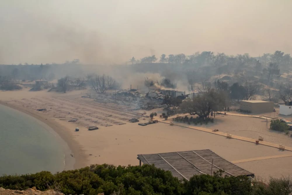 A wildfire burns next to a beach near Lindos. Local media reported the fires reached three hotels, whose clients had already been evacuated.