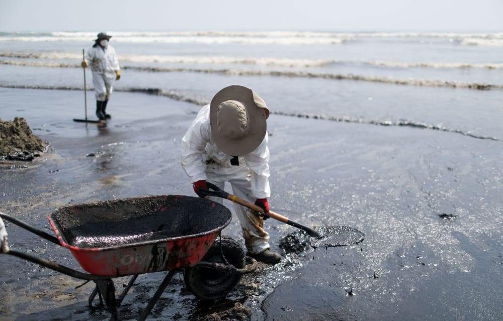 Workers clean up spilled oil, near Ventanilla, on January 18.