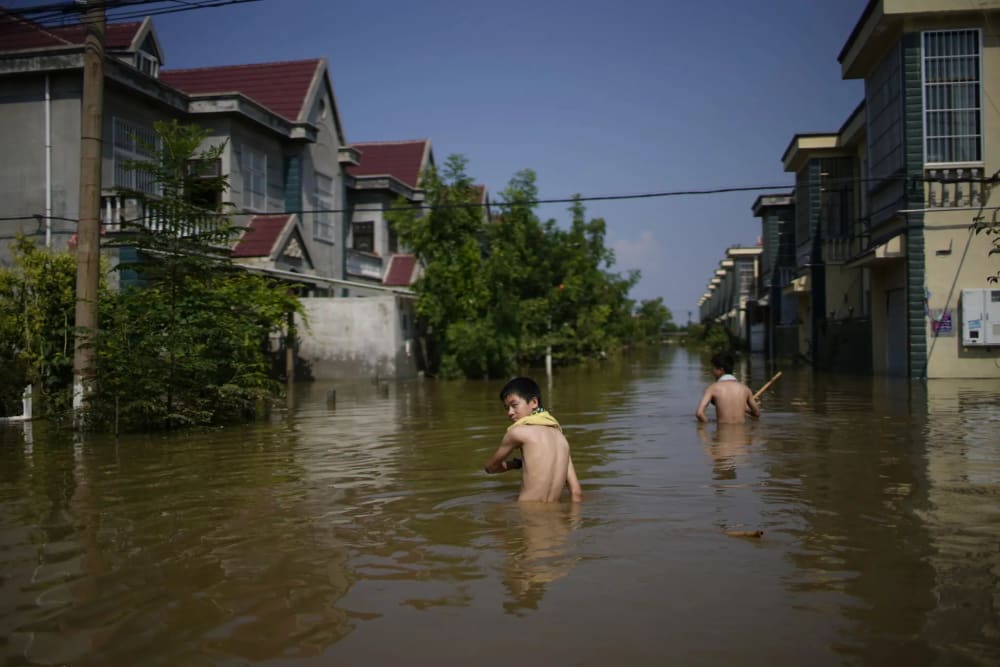 Children wading through floodwaters in Xinxiang, a town in central China, Apr 22, 2024.