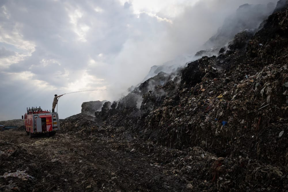 A firefighter works to douse fire as smoke billows from burning garbage at the Ghazipur landfill site in New Delhi, India, April 22.