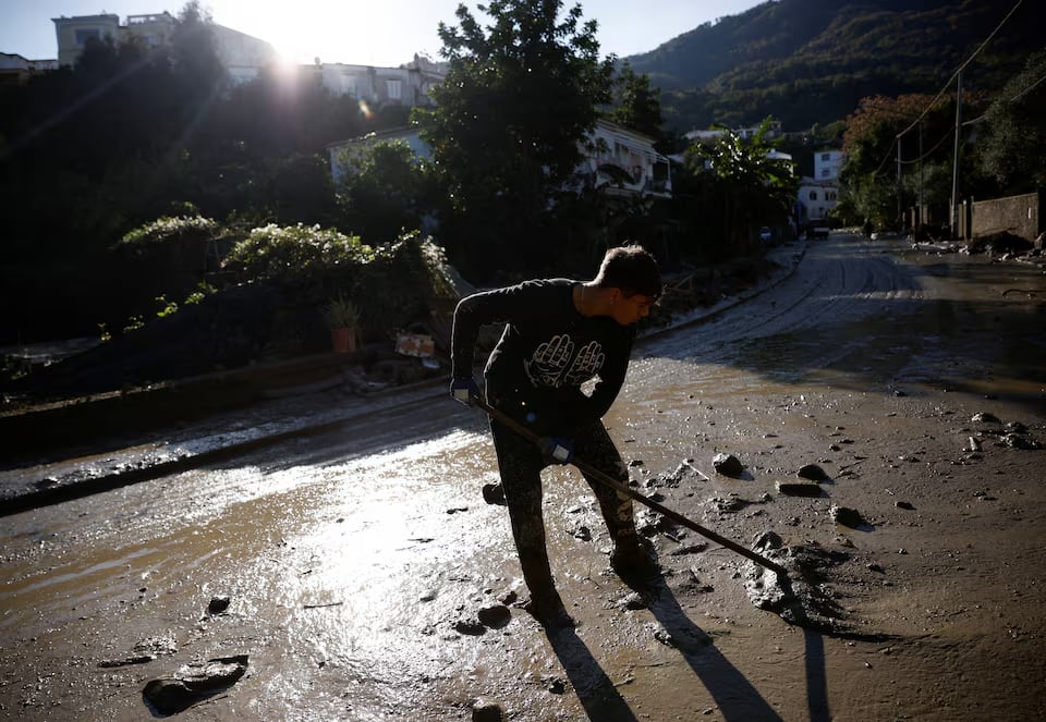 A person cleans up a street covered in mud, following a landslide on the Italian island of Ischia, Italy November 28, 2022. REUTERS/Guglielmo Mangiapane