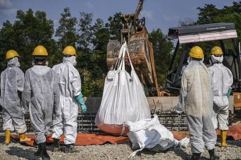 Emergency personnel in protective suits prepare to clean up the Sungai Kim Kim river in Pasir Gudang, Malaysia, on March 14, 2019