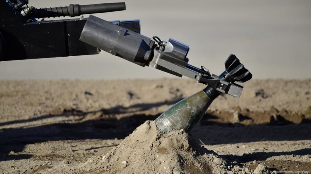 A remote-controlled robot known as tEODor is used to grab a grenade with a manipulator arm.