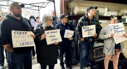 Morrow County residents meet with Oregon Sen. Jeff Merkley about nitrate contamination in their water. They hold up signs showing the nitrate levels in their water.
