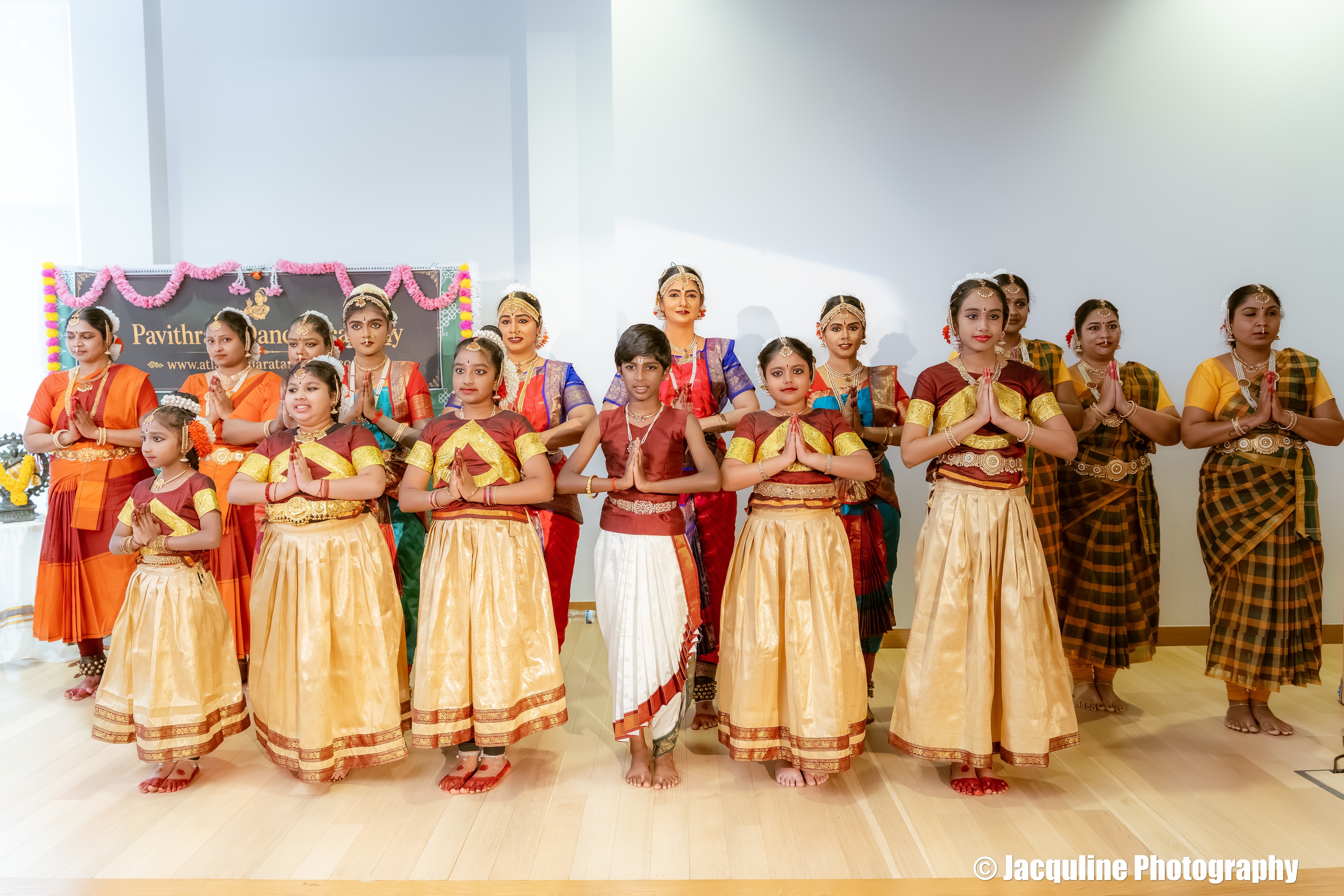 Bharatanatyam dancers performing on stage in traditional red and gold costume