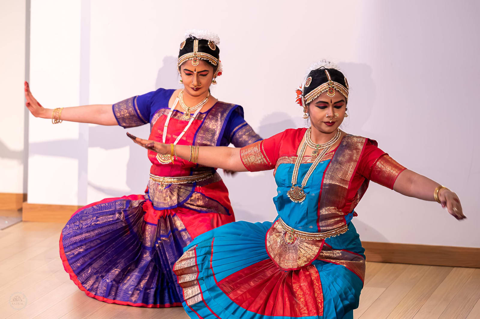 Two dancers perform classical Indian dance in traditional colorful costumes