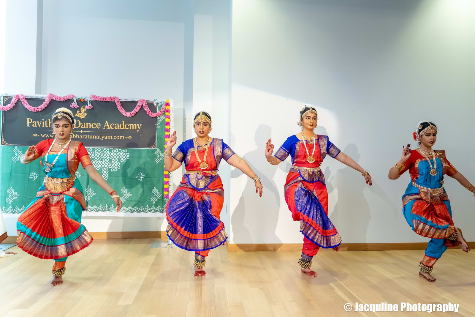 Four dancers performing classical Indian dance in colorful traditional costumes on stage