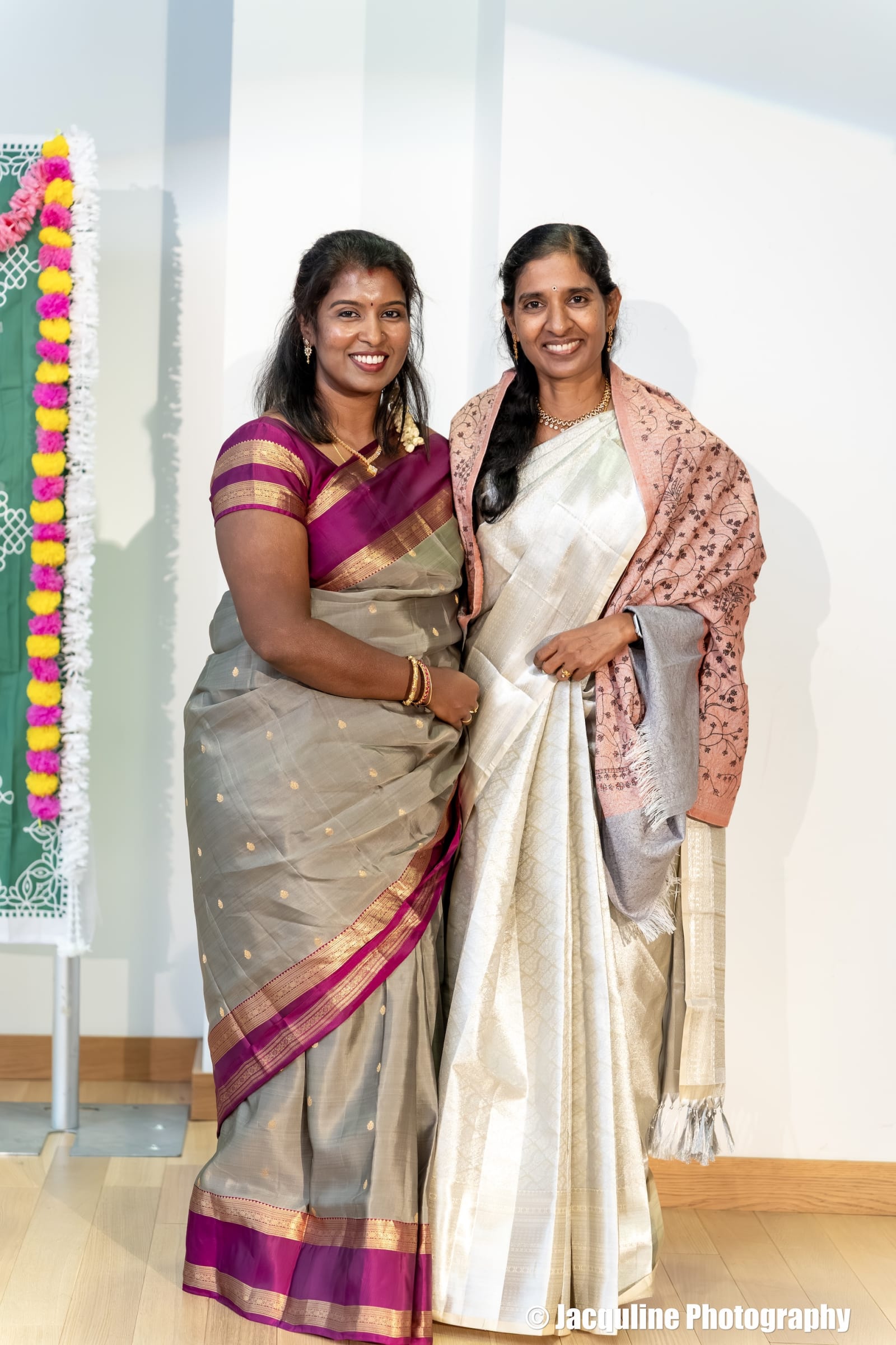 Two women in traditional Indian sarees posing indoors