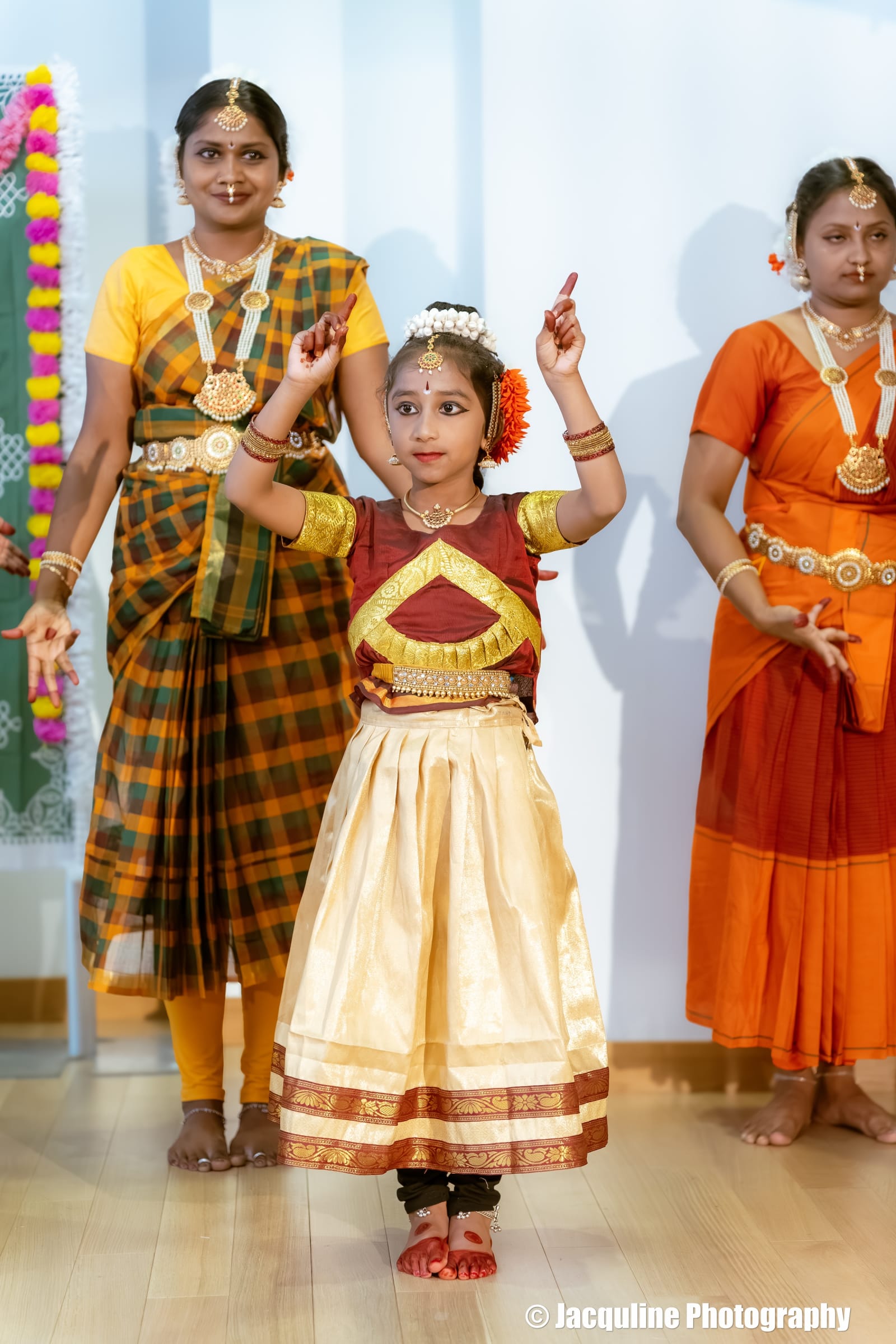 Three girls performing classical Indian dance in traditional costumes