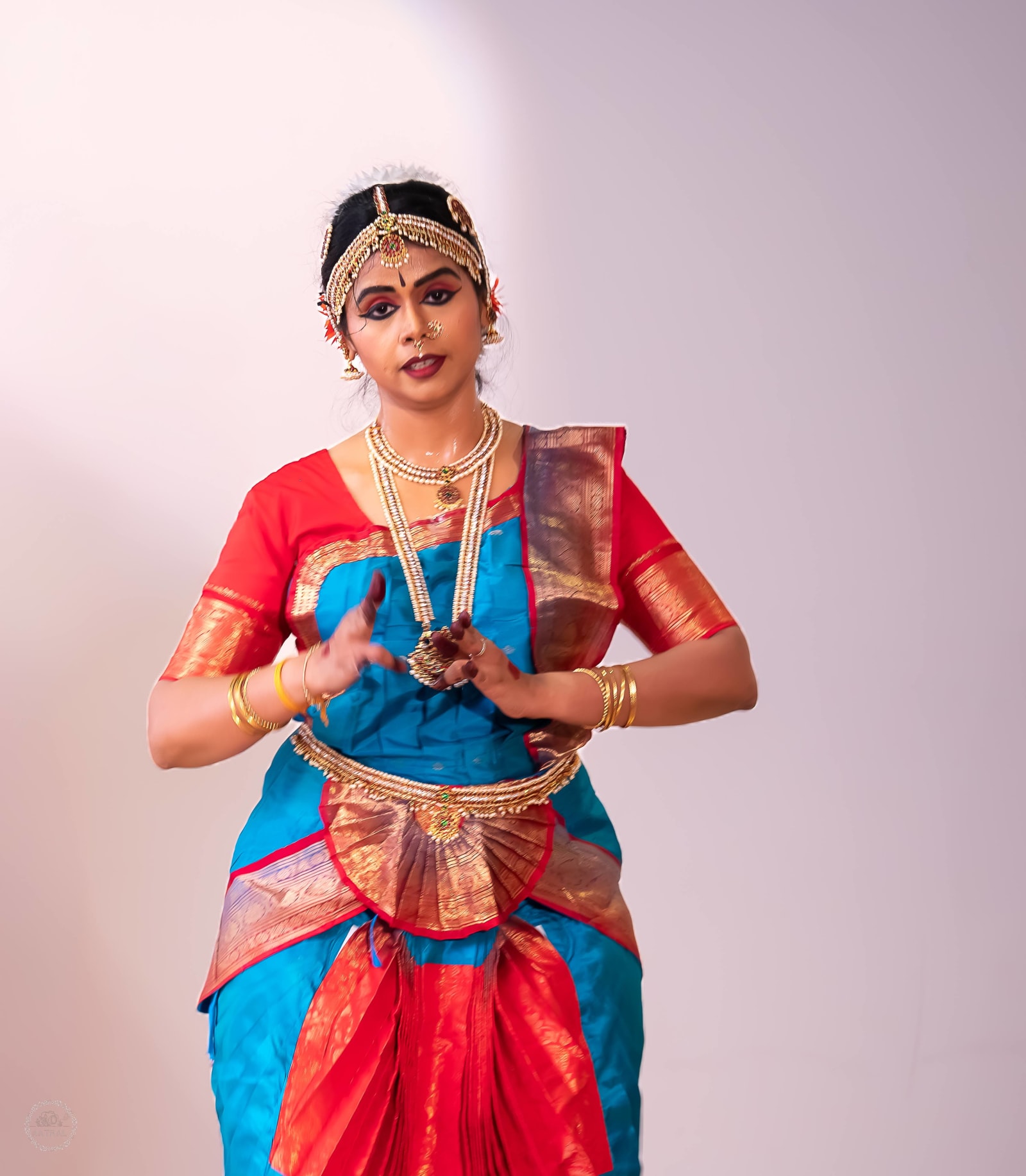 Woman in traditional Indian classical dance costume against neutral background