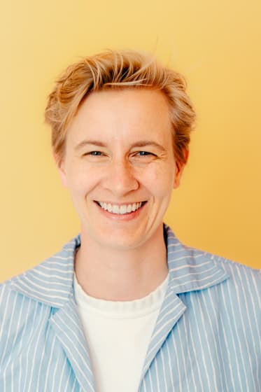 Smiling portrait of a business owner against a yellow wall