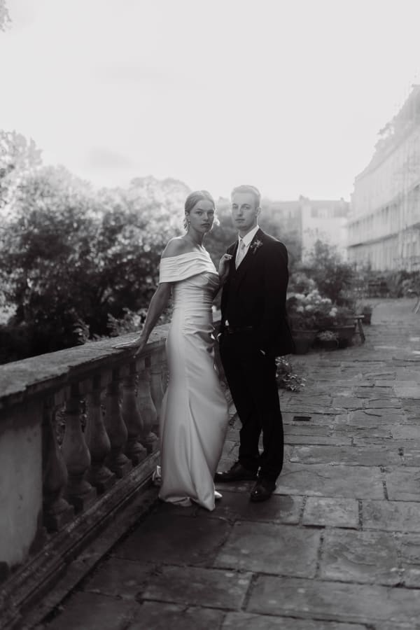 Black and white portrait of a bride and groom on a stone terrace