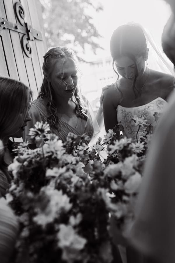 Black and white photo of the bride and bridesmaids at the church door with her bouquet