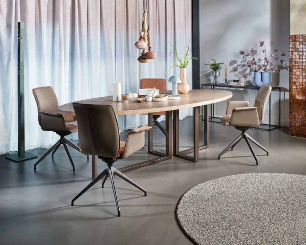 Modernes Esszimmer mit Drehsesseln, schlichter Tischplatte und stilvoller Lichtstimmung vor großen Fenstern. Design-Esszimmer mit hellem Tisch, gepolsterten Drehstühlen, Pendelleuchten und Teppich vor bodentiefer Fensterfront