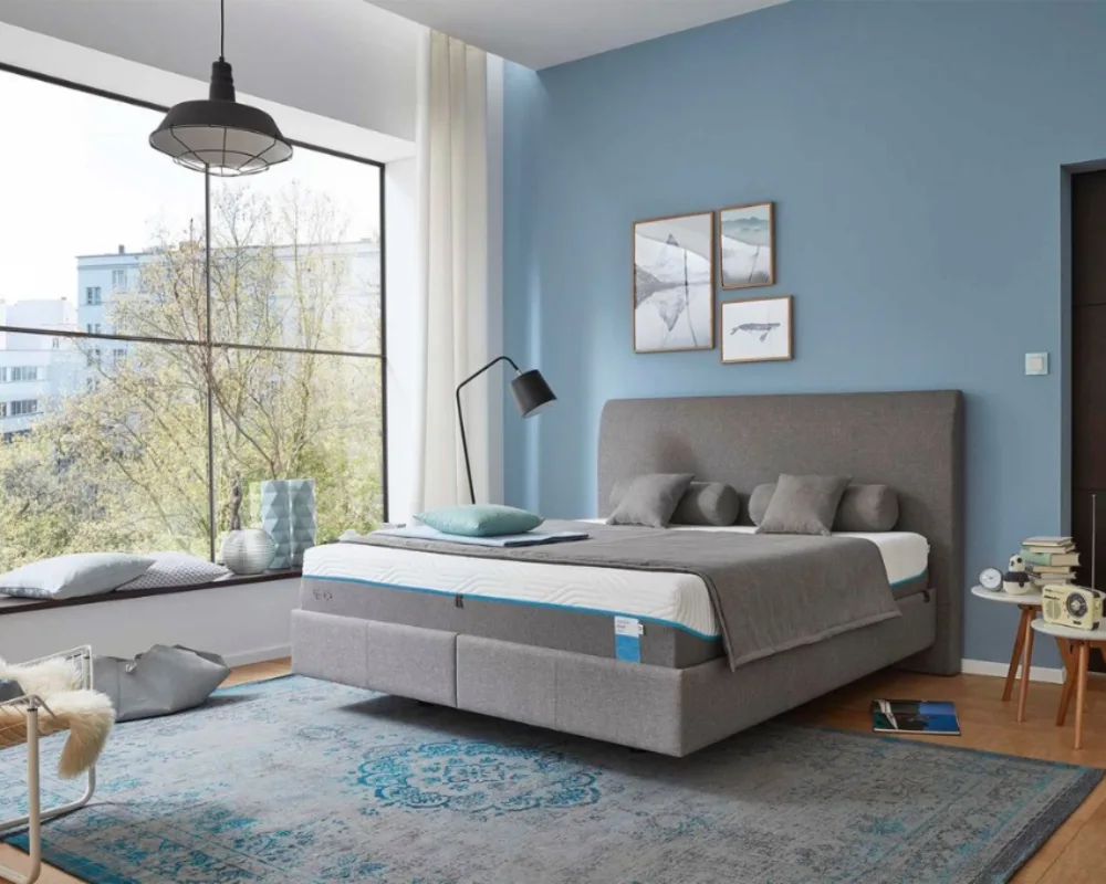 Tempur Schlafsystem in modernem Schlafzimmer Großes Bett mit Tempur Matratze in stilvoll eingerichteter Wohnung mit blauem Teppich