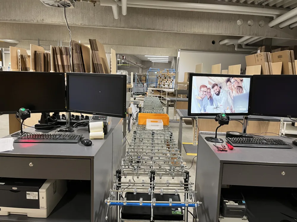 Versandzentrum mit Packstationen Blick auf Packstationen und Monitore in einem modernen Logistiklager