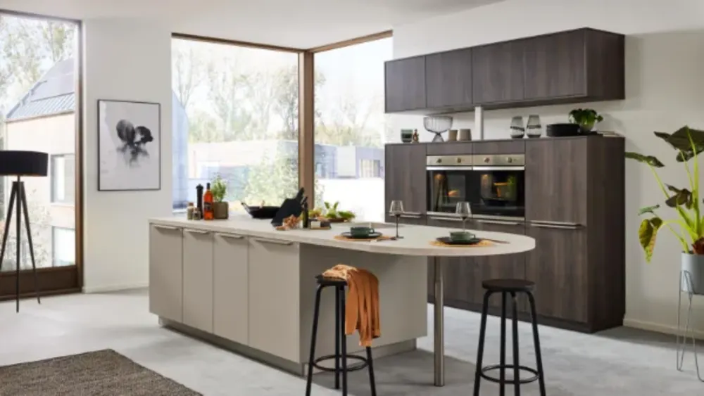 Holzküche Moderne Küche mit Kochinsel in Sandbeige, dunklen Holzfronten, runder Theke und großen Fenstern mit Eckverglasung.