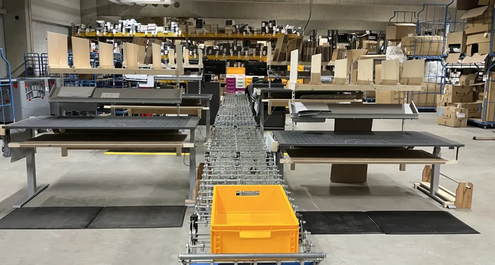 Versandzentrum – Mobile Ansicht Förderband mit gelber Transportbox in einer großen Versandhalle