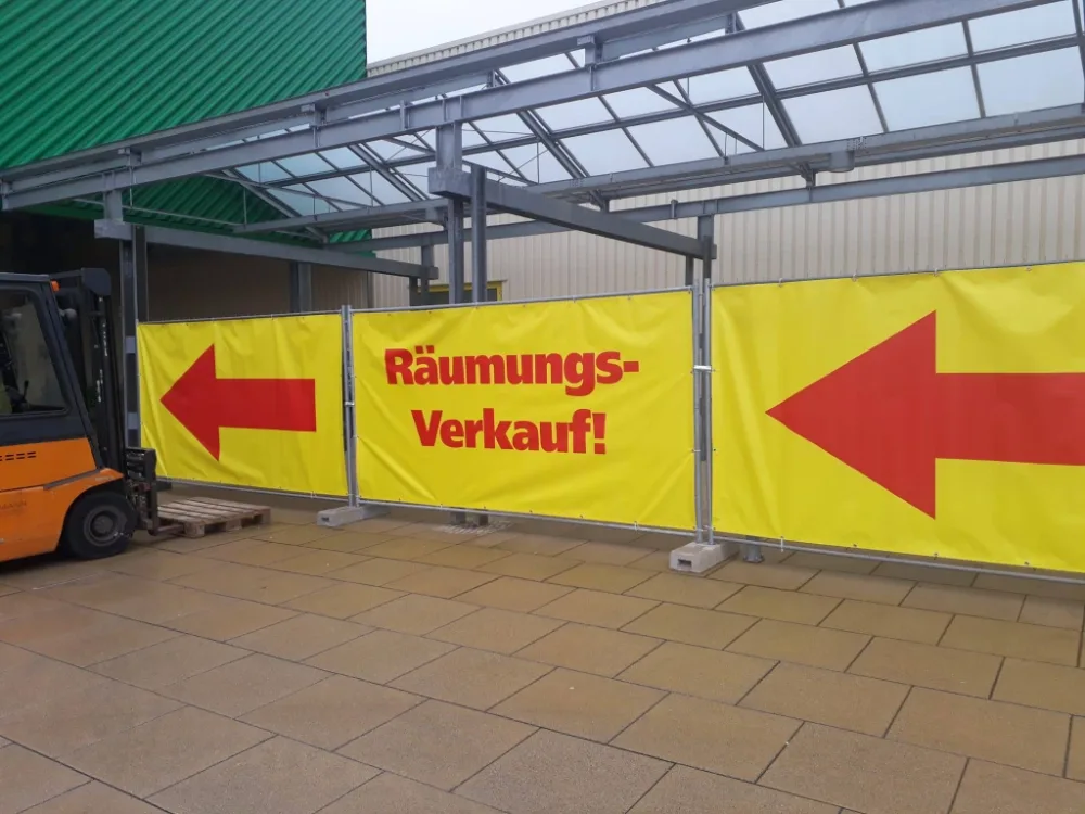 Gelbes Banner mit rotem Schriftzug „Räumungsverkauf!“ und zwei roten Pfeilen zeigt den Weg zur Aktion. Gelbes Banner mit rotem Schriftzug „Räumungsverkauf!“ und zwei roten Pfeilen zeigt den Weg zur Aktion.