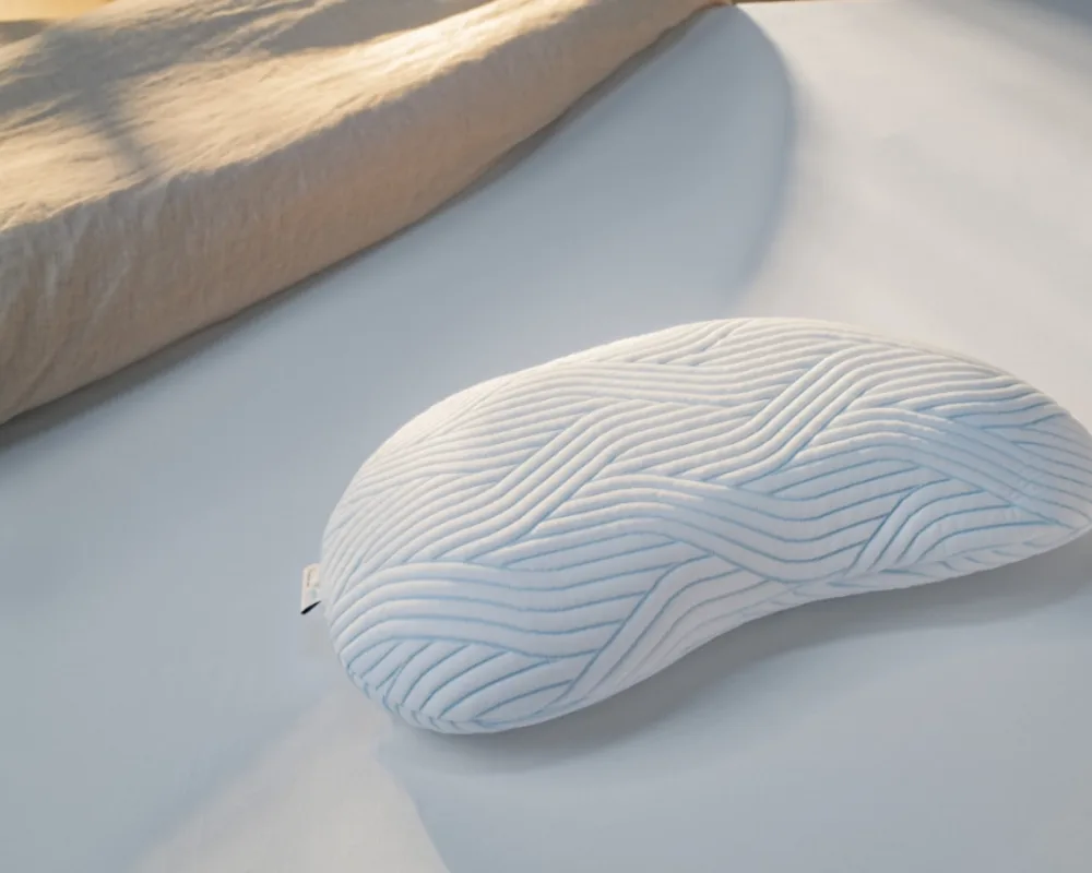 Ergonomisches Tempur Nackenkissen auf Bett Orthopädisches Kissen mit konturierter Form für optimalen Nackenhalt auf hellem Laken