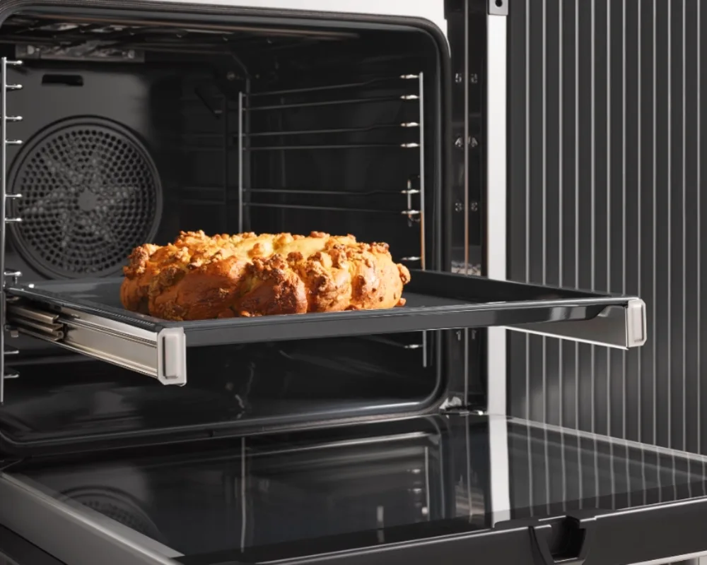 Miele Backofen mit Auszug und Backware Miele-Backofen mit Teleskopauszug, darin ein goldbrauner Backware auf mittlerer Ebene