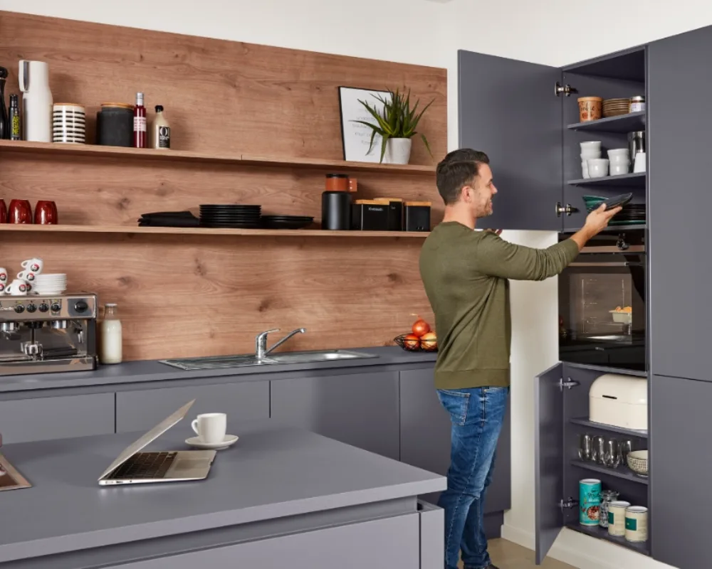 Vorratsschrank mit Auszug in der Interliving Küche Mann öffnet praktischen Vorratsschrank mit Innenauszügen, moderne Küche mit Holzrückwand