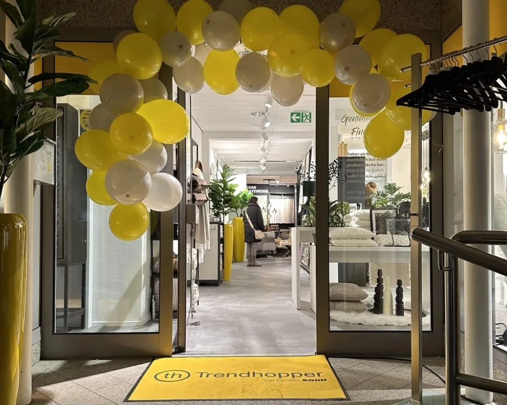 Trendhopper-Eingang mit Ballons. Eingangsbereich von Trendhopper bei Möbel Bohn mit gelb-weißer Ballongirlande und Deko.