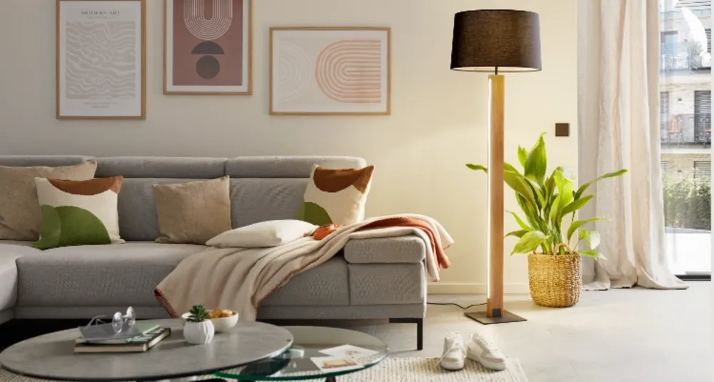 Headerbild Leuchtenkategorie Mobile Wohnzimmerszene mit Sofa, Bilderwand, Kissen und Stehleuchte im natürlichen Tageslicht