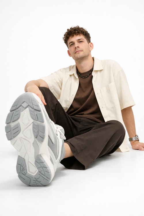 man sitting on clean white surface with oversized sneaker forced perspective