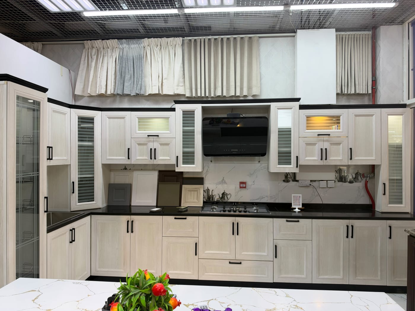 Cream kitchen display with framed cabinet doors, black handles and a dark worktop